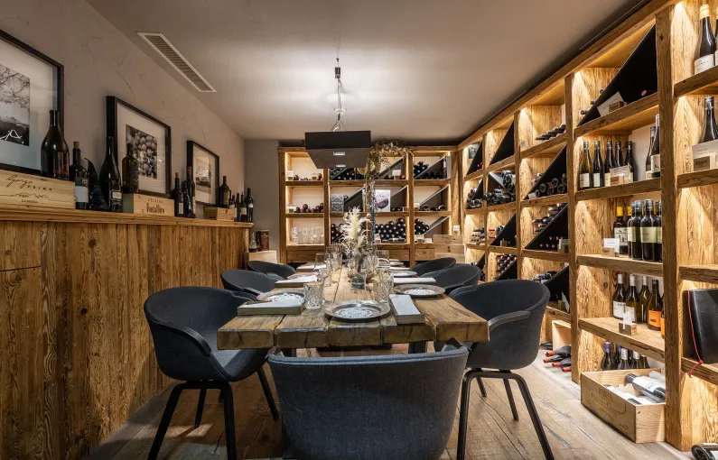 Modernes Wirtshaus mit Holztischen und Regalen voller Weine