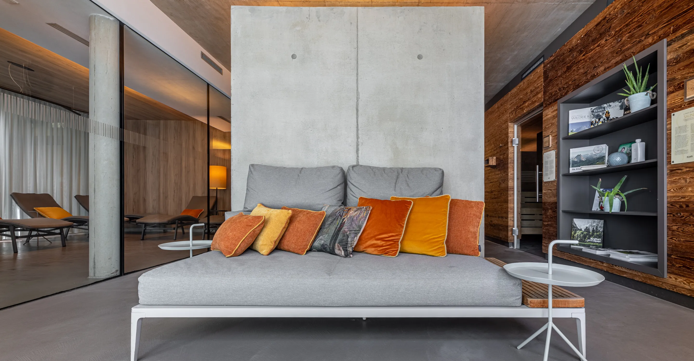 Moderne Lounge mit grauem Sofa und bunten Kissen in einem Wellnessbereich