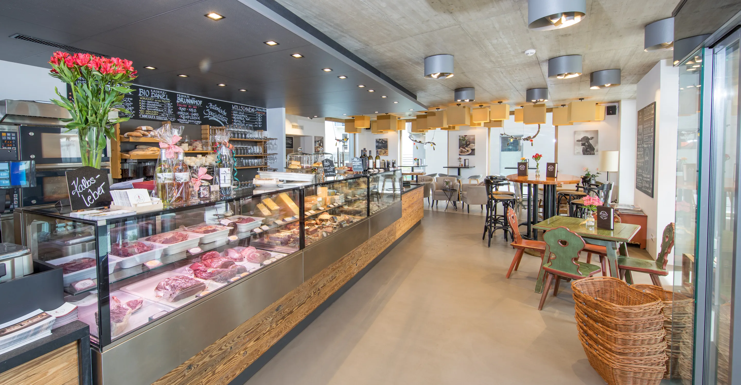 Innenansicht eines Cafés mit Kuchenauslage und Sitzbereichen