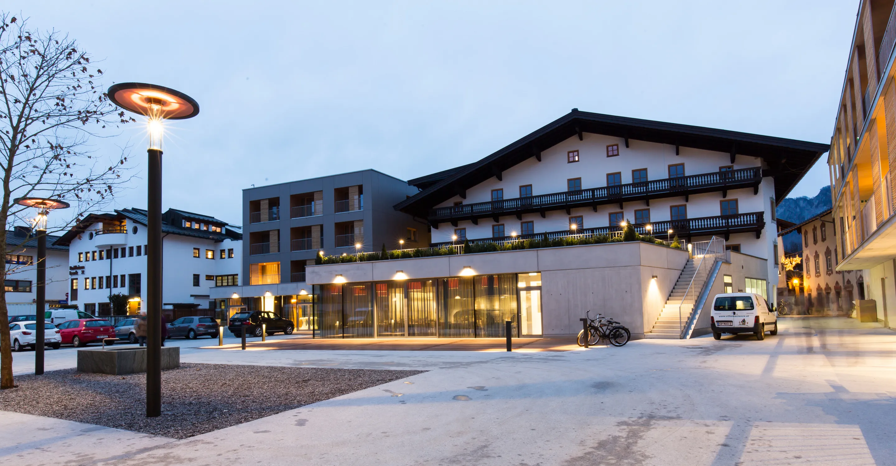 Stadtplatz mit modernen und traditionellen Gebäuden bei Dämmerung.