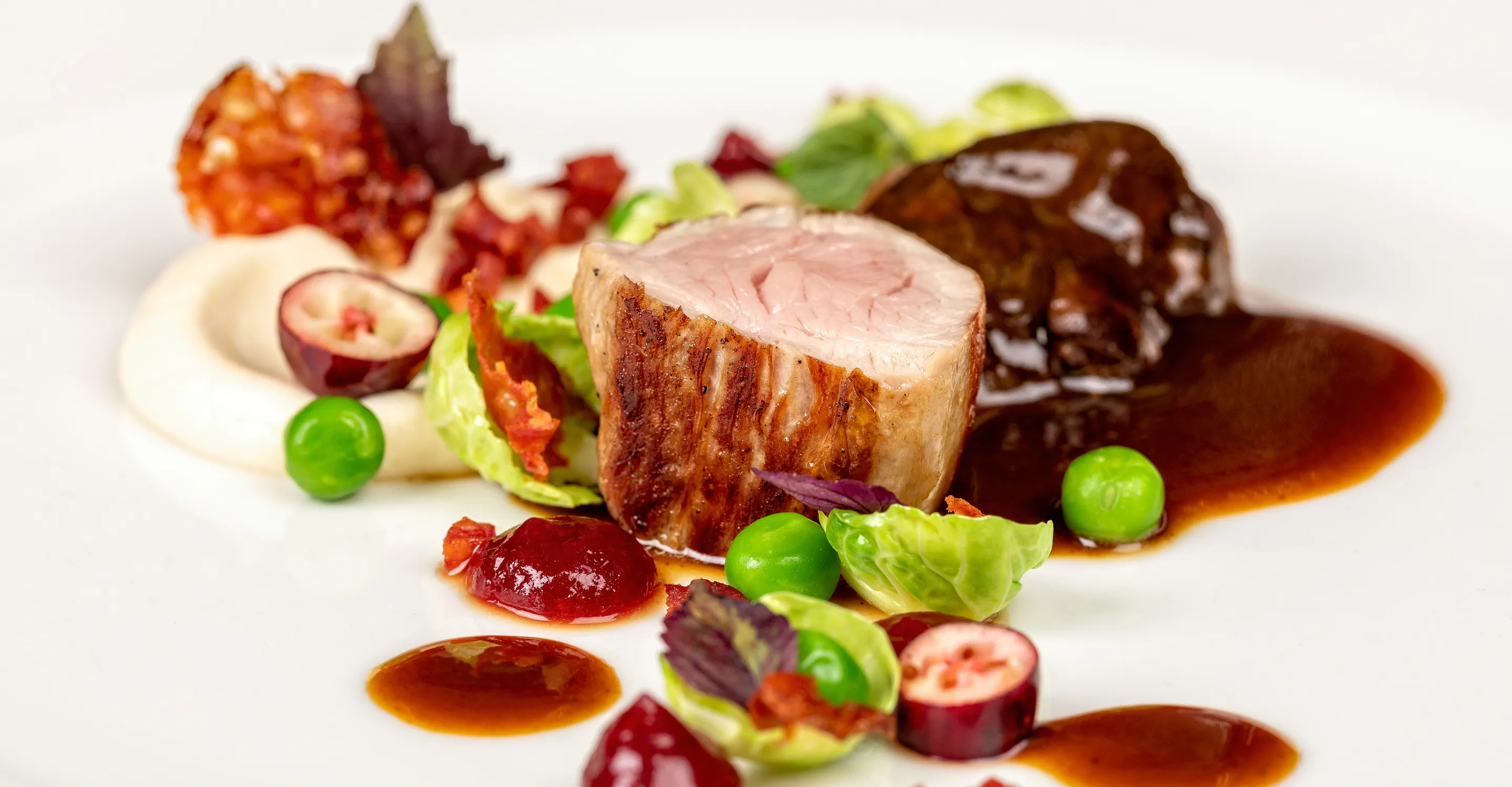 Gourmetgericht mit Fleisch, Gemüse und Saucen auf einem Teller